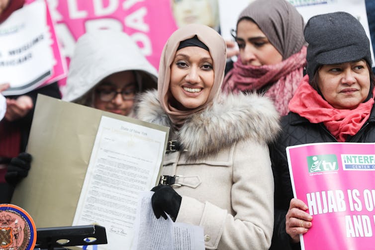 women gather on world hijab day while holding pink posters