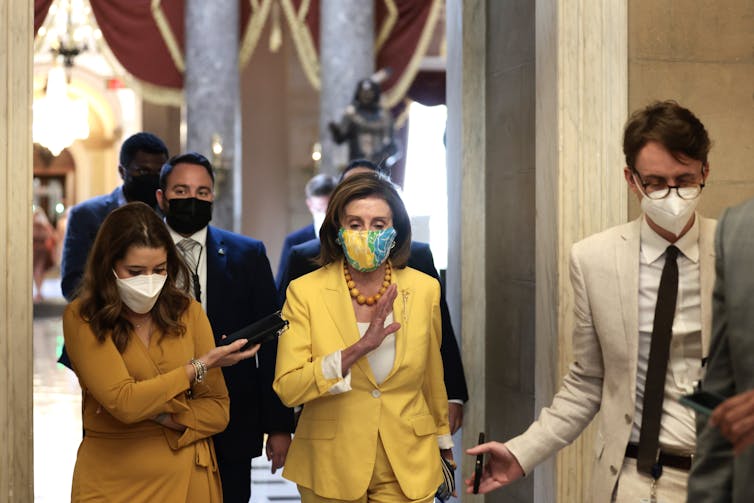 Nancy Pelosi walking and talking with aides. 