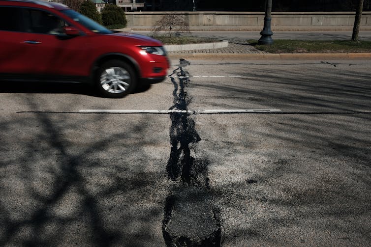 A car drives along a road in need of repair