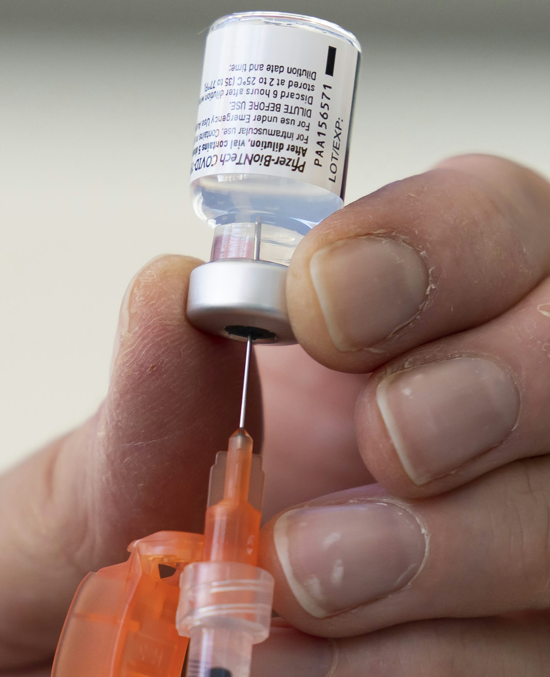 A hand preparing a dose of Pfizer's COVID-19 vaccine