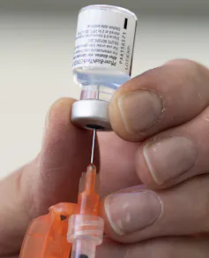A hand preparing a dose of Pfizer's COVID-19 vaccine