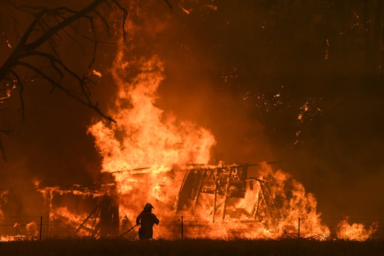 firefighter and bushfire engulfing house