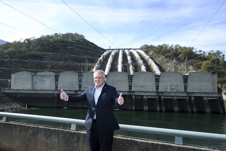 Man gives thumbs up in front of hydro project