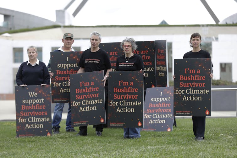 Bushfire survivors hold signs in front of Parliament House