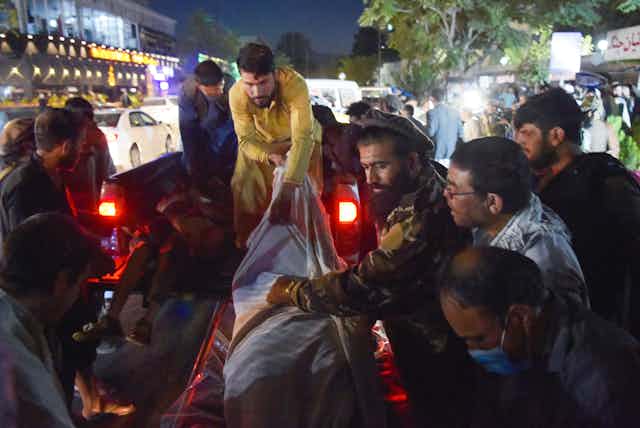 Voluntarios y personal médico descargan cadáveres de una camioneta frente a un hospital en Kabul.