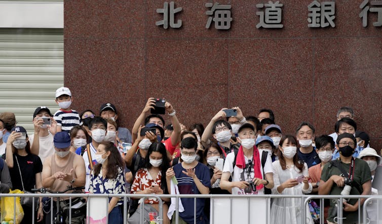 A crowd of masked people watching a marathon event at the Tokyo Olympics
