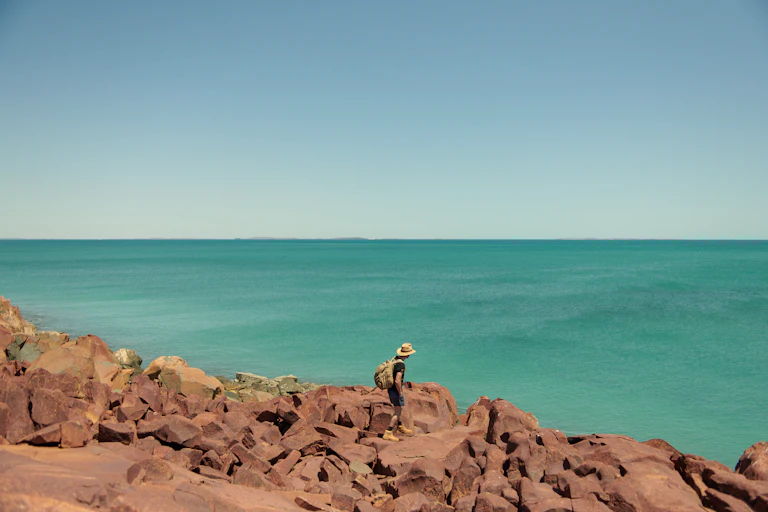 A man walking on rocks near the ocean.