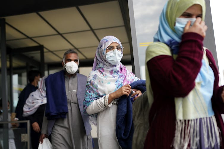 A line of Afghan men and women wearing face masks at Washington's Dulles Airport, August 2021.
