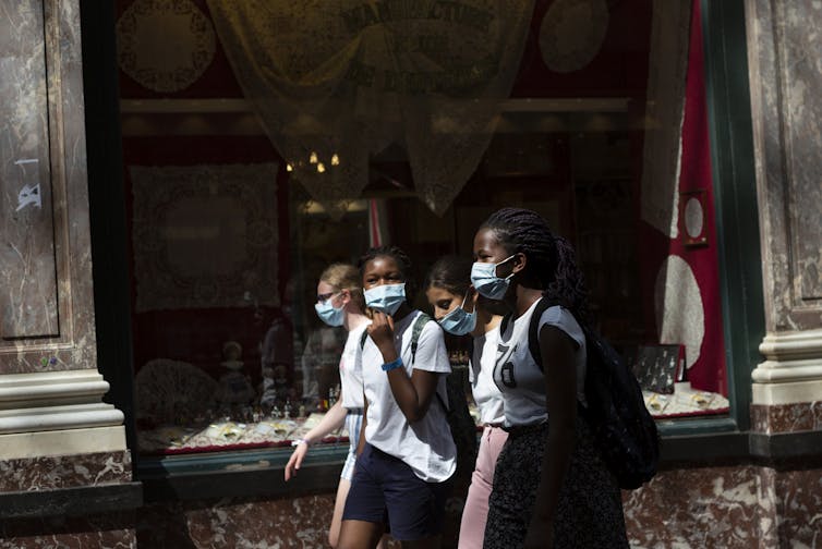 Des fillettes portant un masque marchent dans la rue