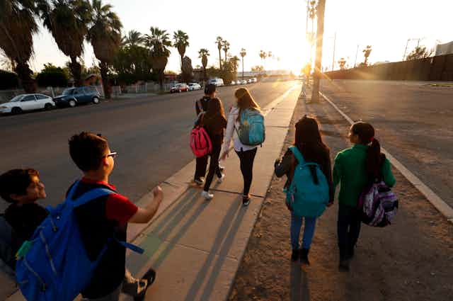 Children with backpacks walk to school in the morning