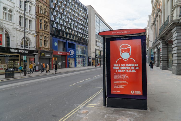 An empty London street during lockdown, with a COVID warning poster on a bus stop