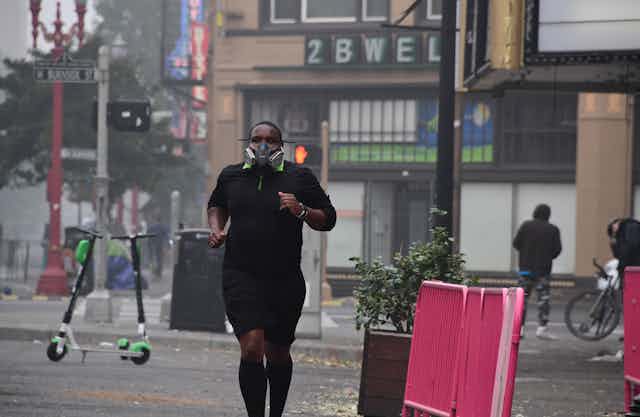 A young man wearing a respirator runs past stores in Portland