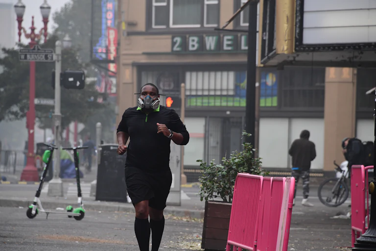 A young man wearing a respirator runs past stores in Portland