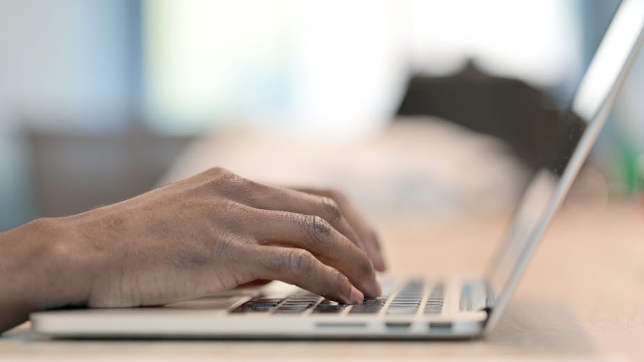Male hands rest on a laptop keyboard.
