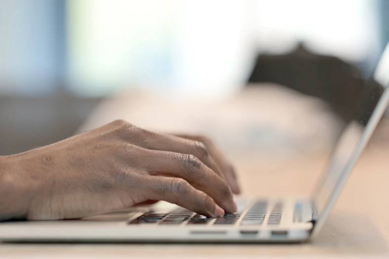 Male hands rest on a laptop keyboard.