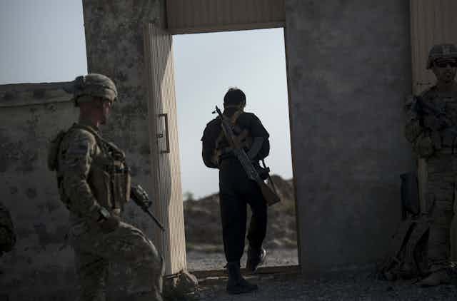 A member of the Afghan police and US soldiers leave a school that will be used as a polling station near Kandahar Airfield.