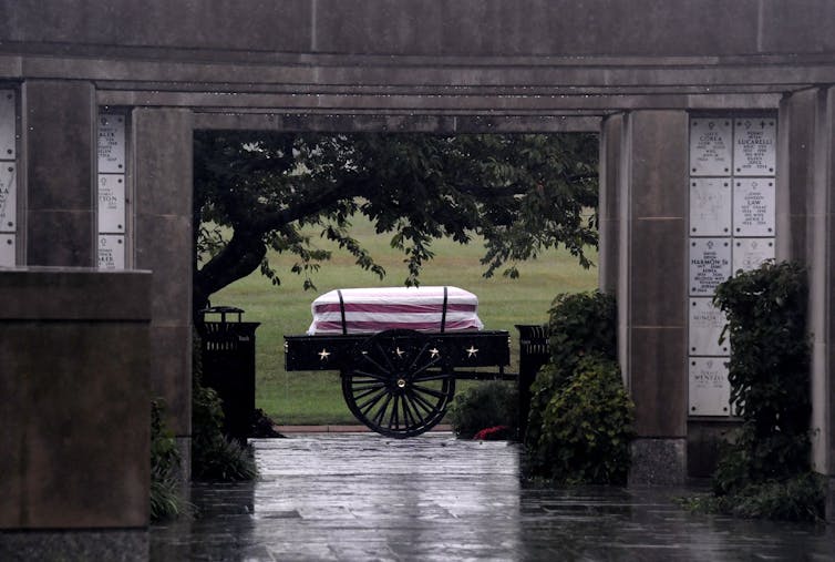 The casket of a US soldier is seen through a doorway during a full military honors burial ceremony