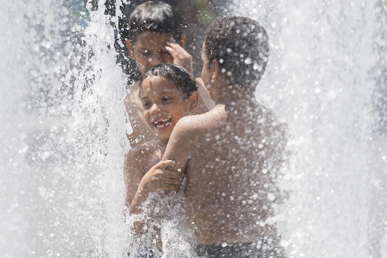 Children playing under the water of a fountain