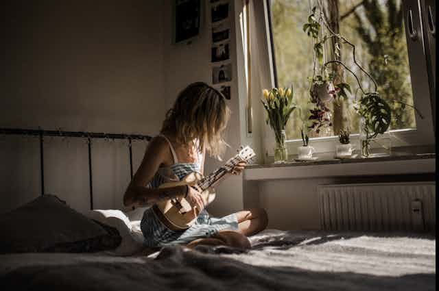 A woman plays a ukulele 