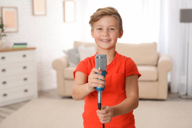 Young boy holding a microphone in the living room.