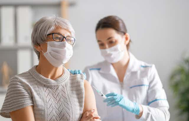 A senior woman receives a vaccination.