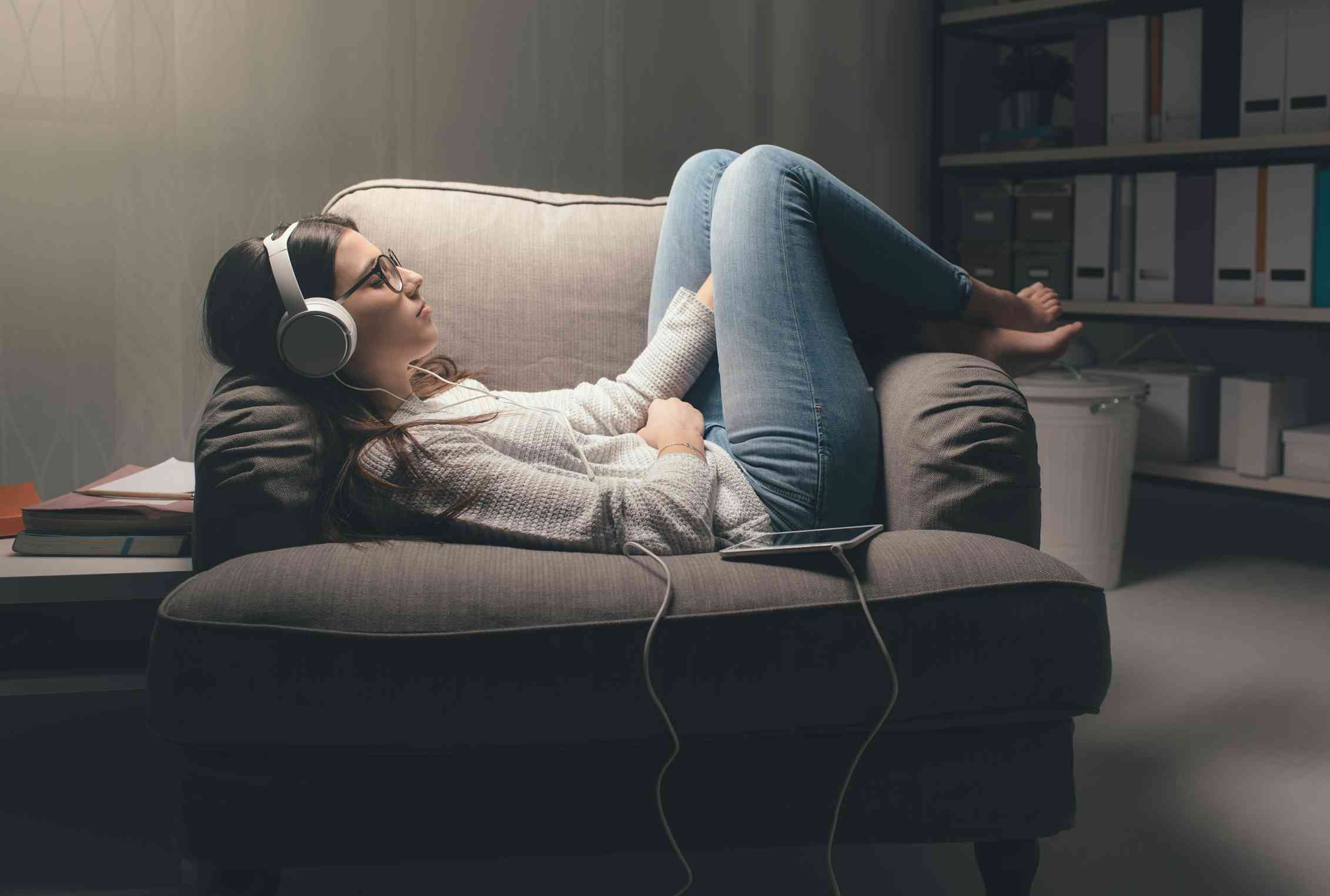 A woman on a lounge chair with headphones.