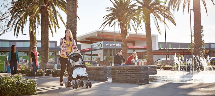 woman pushes pram in front of supermarket