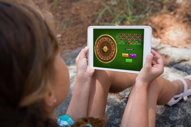 A woman holds a tablet with gambling software on it