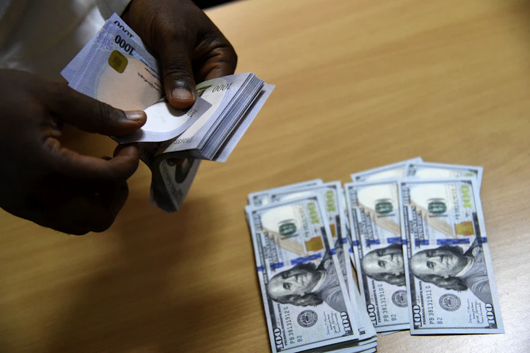 Man counting some Naira notes while some Dollar notes are on the table