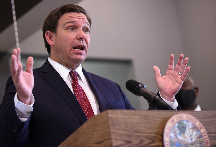 A man in a suit speaks at a podium.