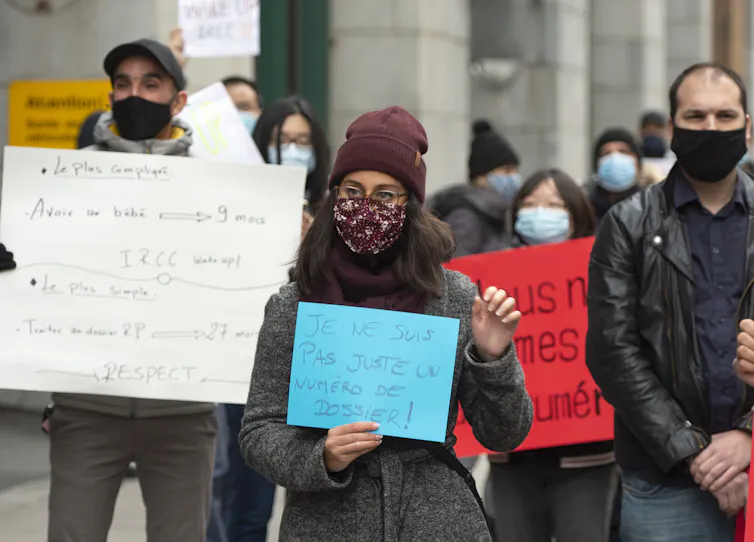 Des manifestants, portant le masque, brandissent des pancartes