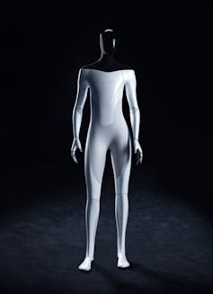 A humanoid robot with a black head and shoulders and white body with the name Tesla across its chest