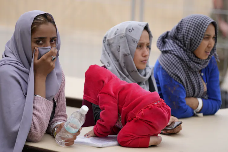 Des femmes voilées assises et un bébé