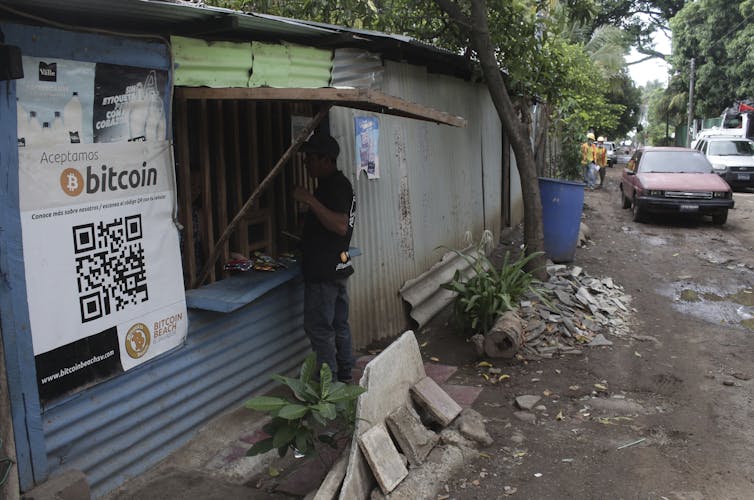 A man in Tamanique, El Salvador, makes a purchase at the opening of a small store that has a sign that says it accepts bitcoin.