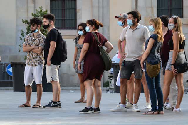 Small crowd of people wearing masks standing in a public space