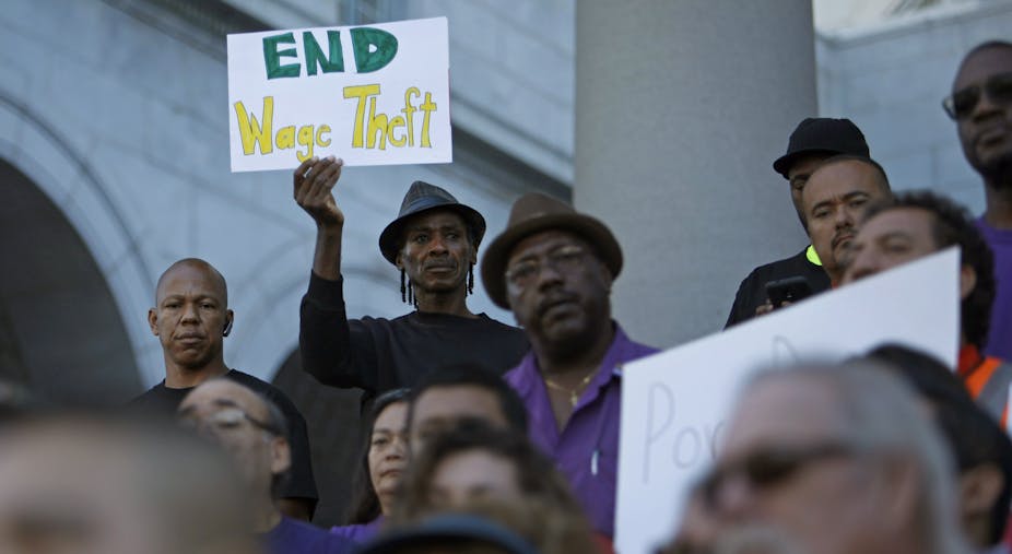 A man holds a sign saying, 'End Wage theft' at a protest over low wages in Los Angeles. 