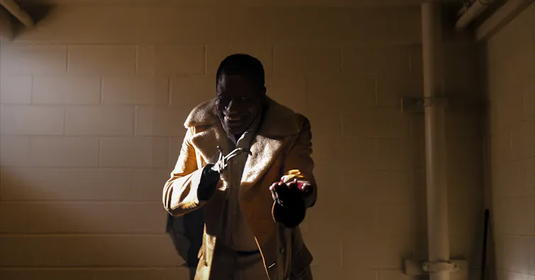 Man in coat with hook hand offers candy.