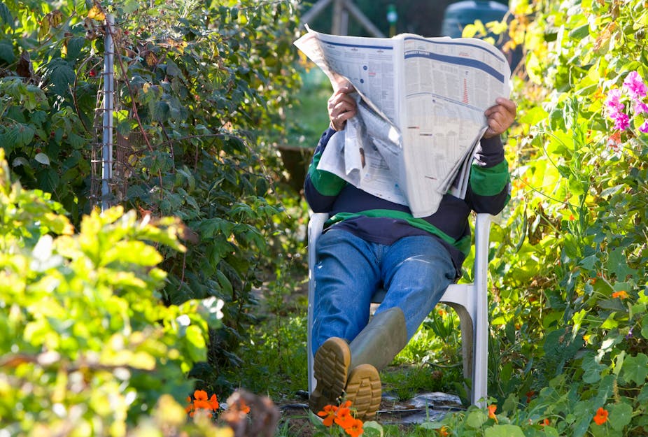A man sitting in his garden reading a newspaper