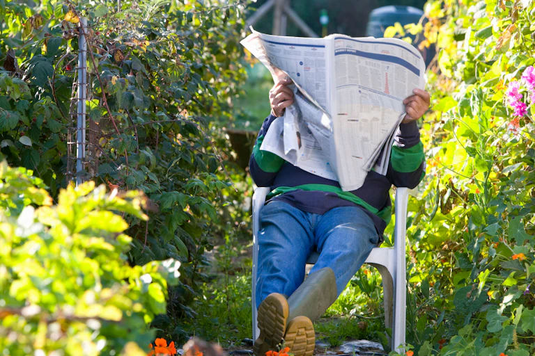 A man sitting in his garden reading a newspaper