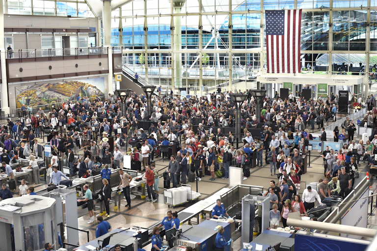 A mass of people wait in a security staging area.