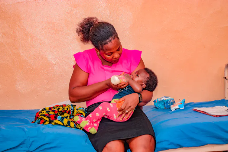 A woman bottle-feeds a newborn infant