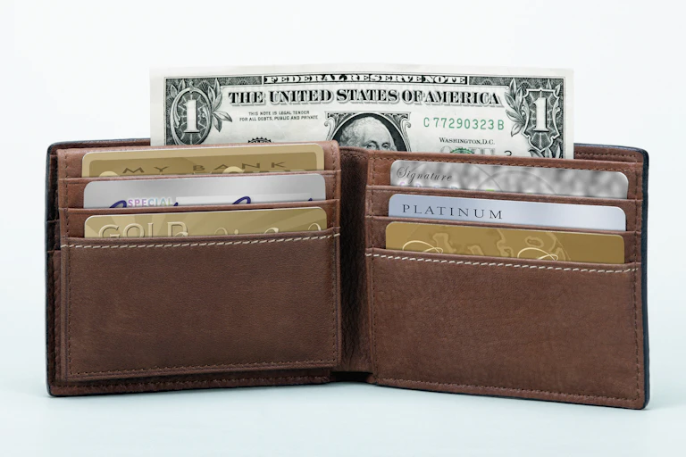 A brown wallet with various credit cards and a dollar bill sticking out the top