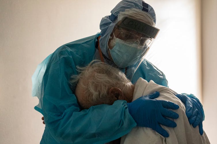 An ICU doctor hugs and comforts a patient in a COVID-19 ICU