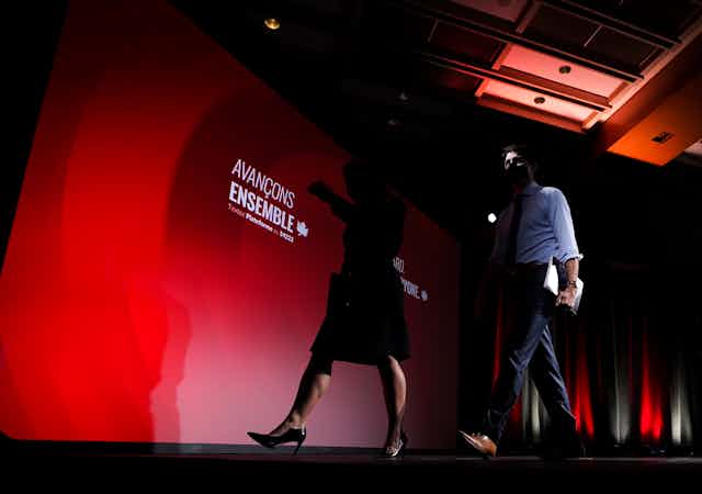 Justin Trudeau and Chrystia Freeland walk off a stage lit with Liberal colours