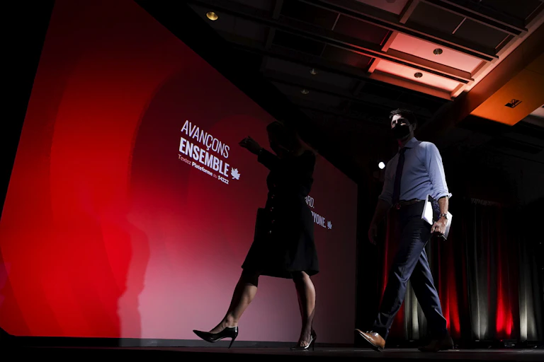Justin Trudeau and Chrystia Freeland walk off a stage lit with Liberal colours
