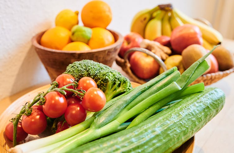 Bowls of oranges, bananas, tomatoes, scallions and other produce are attractively arrayed.