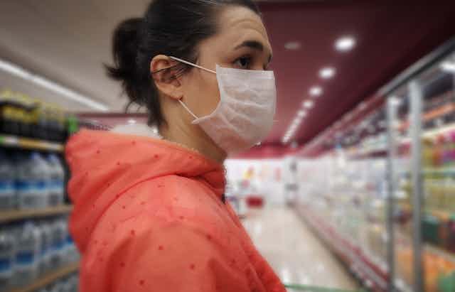 Woman in a face mask gets overwhelmed while grocery shopping.