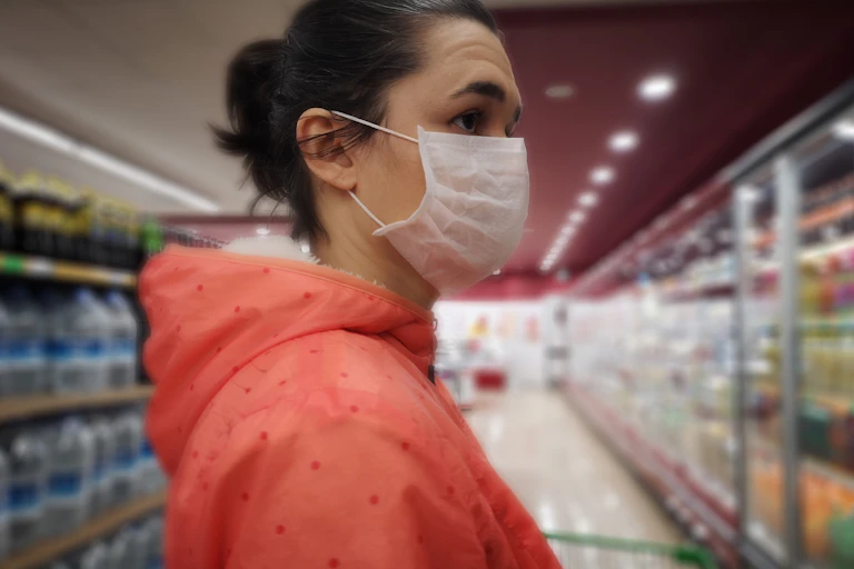Woman in a face mask gets overwhelmed while grocery shopping.