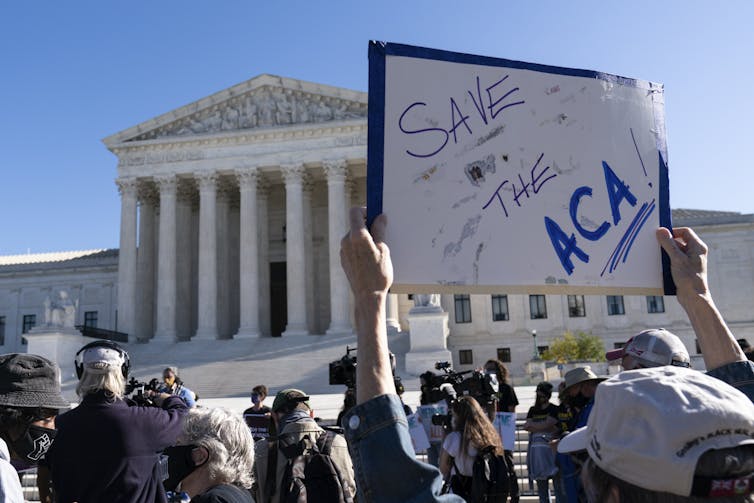 Demonstrator holds a sign saying 'Save the ACA' in front of the U.S. Supreme Court.