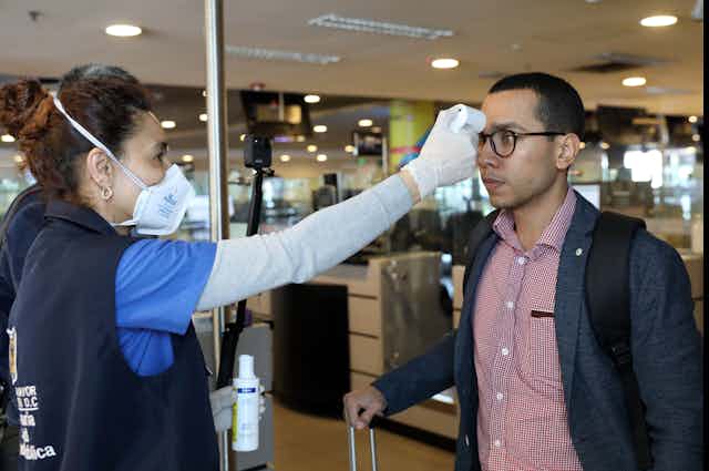 A man has his temperature checked in Colombia.